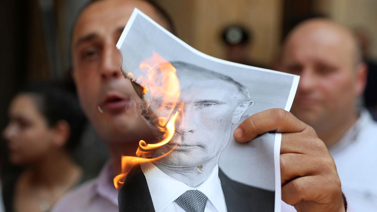 Un protestataire brûle une image du président russe lors d'une manifestation à Tbilissi le 20.06.2019. [Reuters - Irakli Gedenidze]