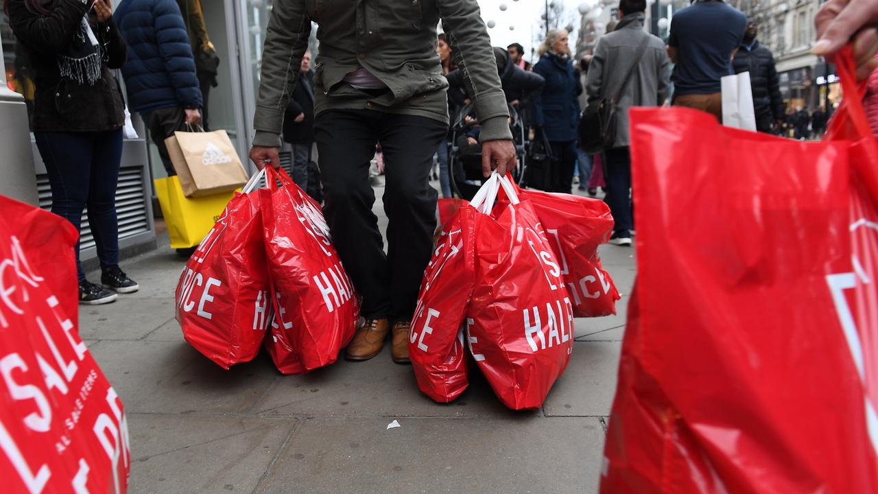 Des passants à Oxford Street, à Londres, les mains pleines de sacs après avoir profité des soldes du Boxing Day. [Keystone - Andy Rain/EPA]