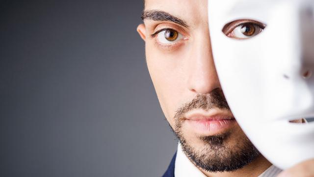 Une homme se cache le visage derrière un masque. [Depositphotos - Elnur_]