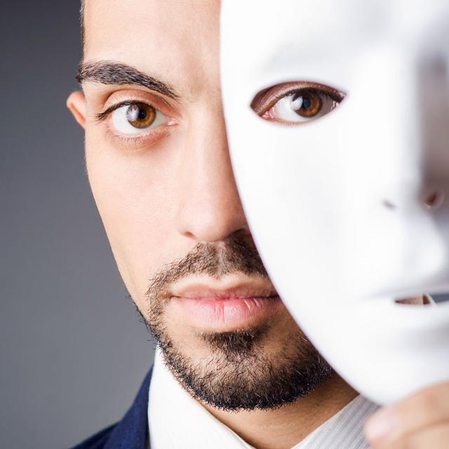 Une homme se cache le visage derrière un masque. [Depositphotos - Elnur_]