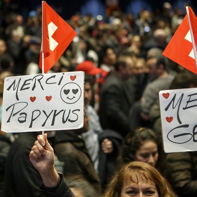 Une femme sans-papiers montre deux panneaux "Merci Papyrus" et "Merci Genève", lors de la séance de présentation du projet-pilote en février 2017. [Keystone - Salvatore Di Nolfi]