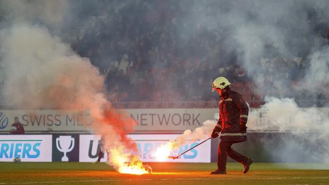 Un pompier intervient pour se saisir d'un engin pyrotechnique lors d'un match entre Sion et Grasshopper. [Keystone - Salvatore Di Nolfi]