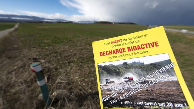 Un document d'un groupement d'opposants  photographié devant les champs sensés accueillir la décharge de la Vernette. [KEYSTONE - Laurent Gillieron]