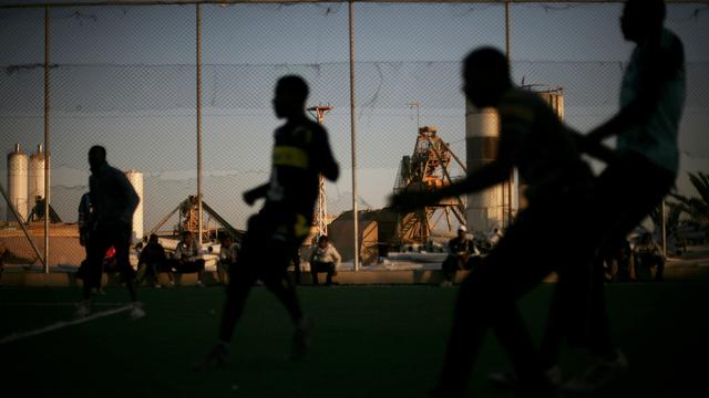 Des jeunes hommes jouent au football dans un camps de réfugiés en Libye. [AP-Keystone - Manu Brabo]