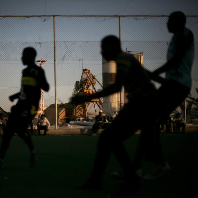 Des jeunes hommes jouent au football dans un camps de réfugiés en Libye. [AP-Keystone - Manu Brabo]