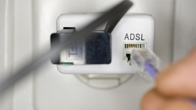 Un usager branche une prise ADSL dans la prise du téléphone fixe. [Keystone - Martin Ruetschi]