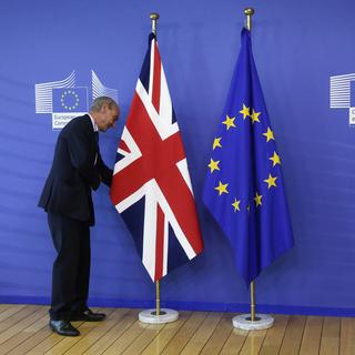 Un employé arrange les drapeaux avant le premier rendez-vous entre David Cameron et Jean-Claude Juncker après le vote du Brexit [EPA/Keystone - Olivier Hoslet]