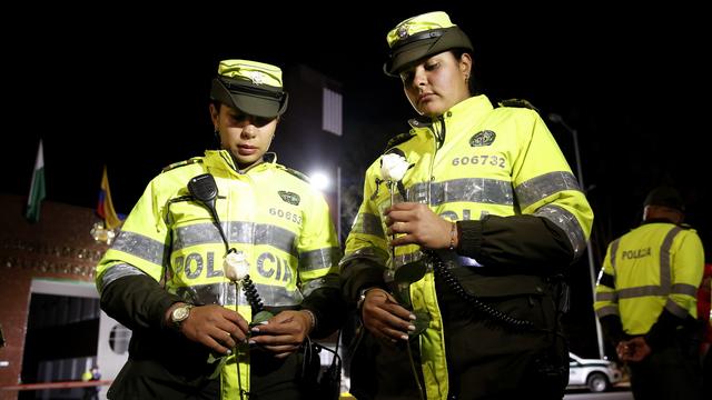 Des policières, fleurs à la main, lors d'une veillée après l'attentat de Bogota. [EPA - LEONARDO MUNOZ]