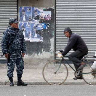 Des soldats boliviens se tiennent devant un poster électoral de l'ex-président Evo Morales à El Alto, dans la périphérie de La Paz. [AP Photo/Keystone - Natacha Pisarenko]