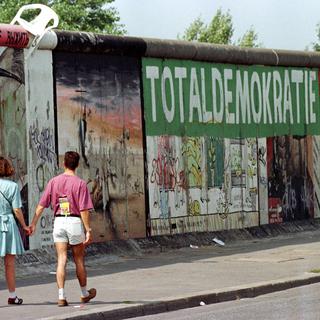 Un couple devant une portion restante du mur de Berlin en 1996. [Reuters - Fabrizio Bensch]