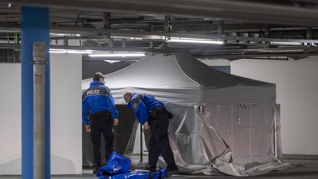 Des policiers genevois s'affairent sur les lieux où un jeune homme a été tué, dans le parking du centre commercial Planète Charmilles. [KEYSTONE - Martial Trezzini]