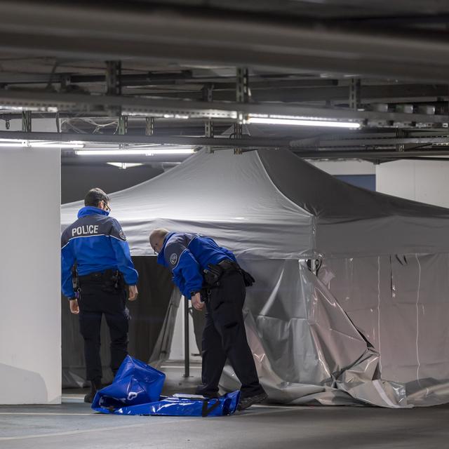 Des policiers genevois s'affairent sur les lieux où un jeune homme a été tué, dans le parking du centre commercial Planète Charmilles. [KEYSTONE - Martial Trezzini]