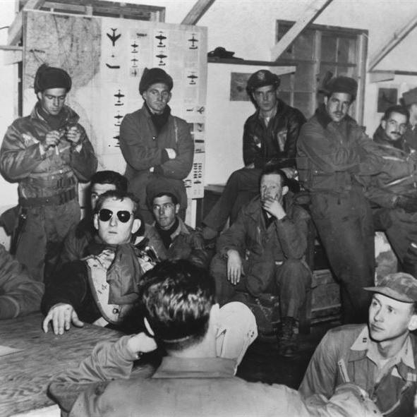Des pilotes et équipages de Mustang de l'U.S. Air Force et de la Royal Australian Air Force au debriefing après une attaque contre les forces adverses au sud-est de Séoul, en février 1951. [U.S. Air Force photo]