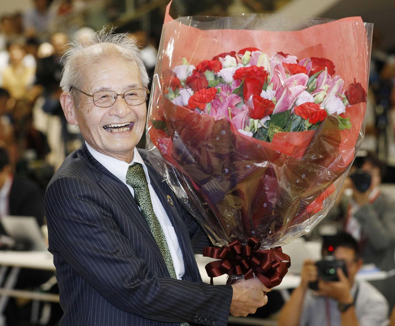 Le chimiste Akira Yoshino, fraîchement nobelisé, pose avec un gros bouquet de fleurs à Tokyo. [Keystone/Kyodo News via AP - Yuta Omori]
