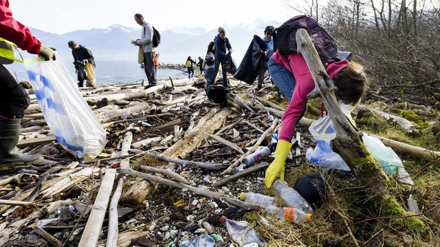 Des bénévoles ramassent des déchets sur les rives du Léman le 7 avril 2018. [Keystone - Jean-Christophe Bott]