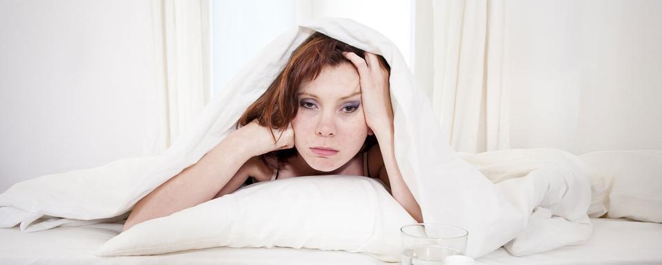 Une femme dans son lit semble désespérée. [Depositphotos - focuspocusltd]