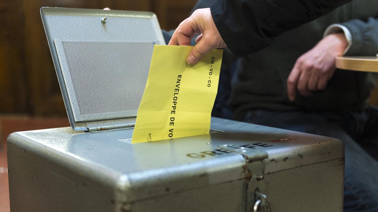 Une enveloppe de vote glissée dans l'urne. [Keystone - Gabriel Monnet]
