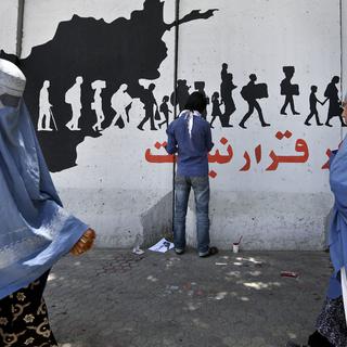 Un artiste afghan peint sur un mur anti-explosion à Kaboul. [Keystone - Rahmat Gul/ AP]