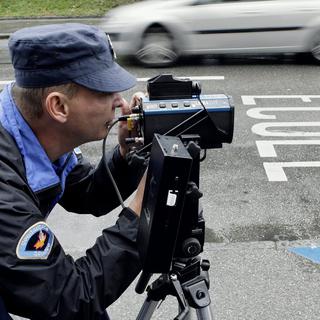 Un policier de la gendarmerie genevoise utilise un pistolet radar (image d'illustration). [Keystone - Salvatore Di Nolfi]