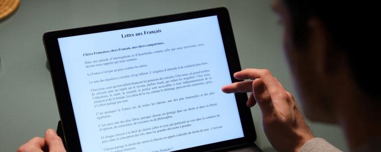 Un homme lit la "Lettre aux Français" d'Emmanuel Macron publiée lundi. [AFP - Ludovic Marin]