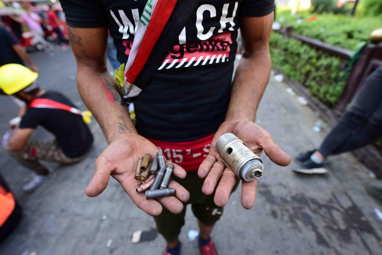 Un manifestant montre les balles et bombes lacrymogènes utilisées en Irak, à Bagdad. [Keystone - MURTAJA LATEEF]