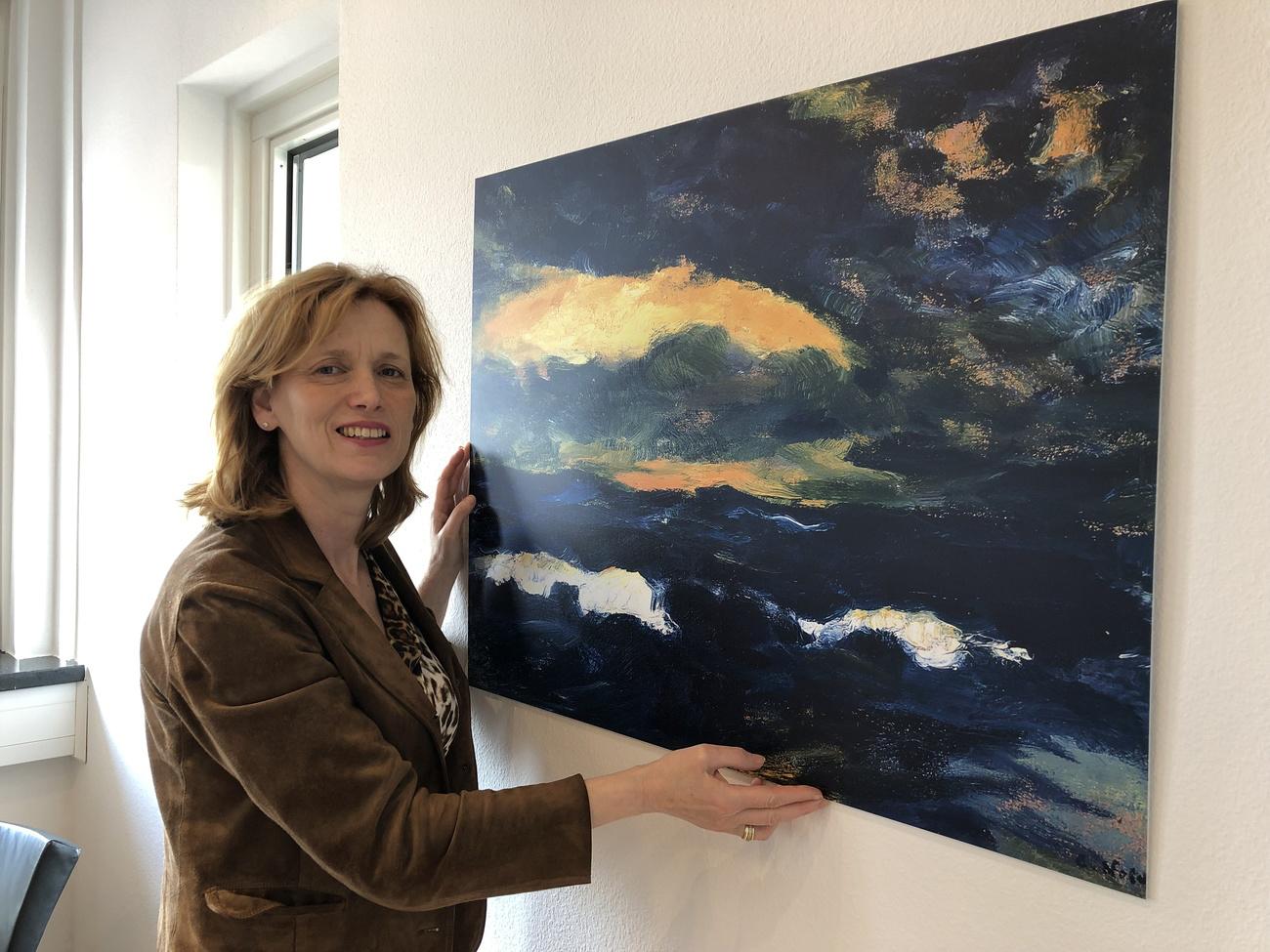 La ministre de la Culture du Schleswig-Holstein Karin Prien pose dans son bureau à côté de la reproduction du tableau d'Emil Nolde intitulé "Durchbrendes Licht" le 11 avril 2019. [Keystone - Andre Klohn]