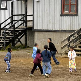 Enfants de l'éthnie Inuit jouant devant une maison en bois dans le village de Tiniteqilaaq. [AFP - PHILIPPE ROY / Aurimages]