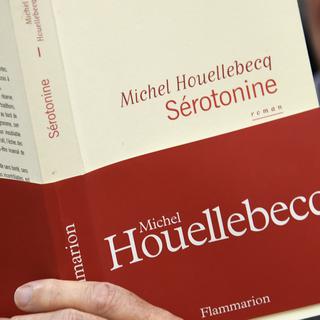 Un homme lisant "Sérotonine", le dernier roman de Michel Houellebecq. [AFP - Bertrand Guay]