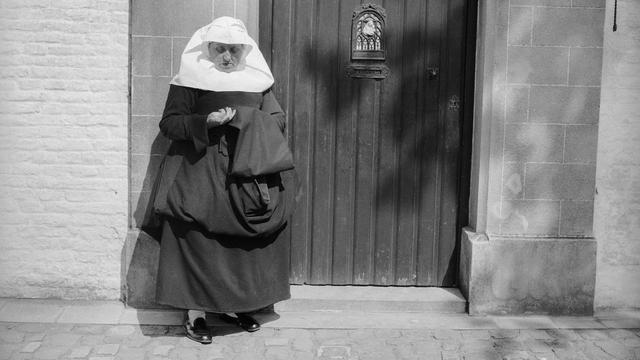 Une femme béguine se tient devant une porte en Belgique. [AFP - Charles Hurault]