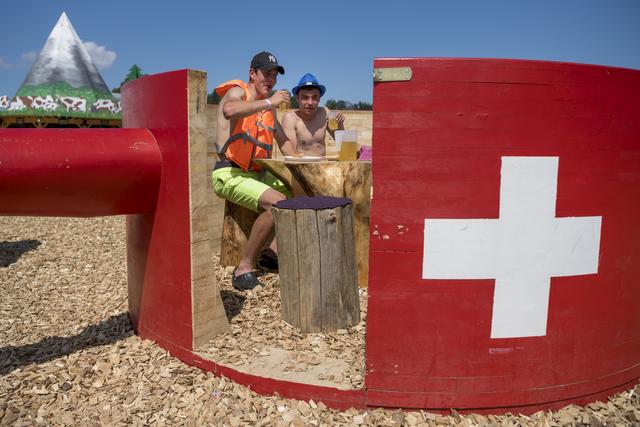 Des jeunes boivent un verre dans un caquelon a fondue géant lors de la fête du 100e anniversaire de la FVJC. [Keystone - Jean-Christophe Bott]