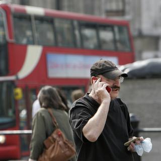Une personne au téléphone à Trafalgar Square, dans le centre-ville de Londres. (image d'illustration) [Keystone - Lefteris Pitarakis]
