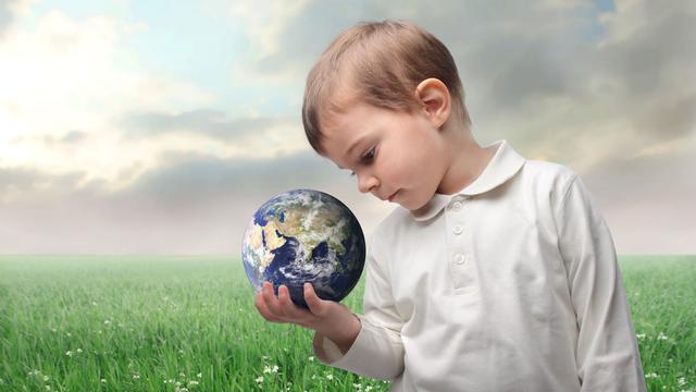 Un enfant regarde la terre qu'il tient dans sa main. [Depositphotos - olly18]