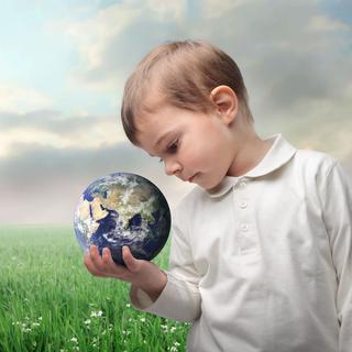 Un enfant regarde la terre qu'il tient dans sa main. [Depositphotos - olly18]
