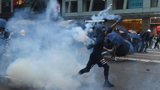 Un manifestant renvoie du gaz lacrymogène en direction de la police à Hong Kong. [AFP - Mohd Rasfan]