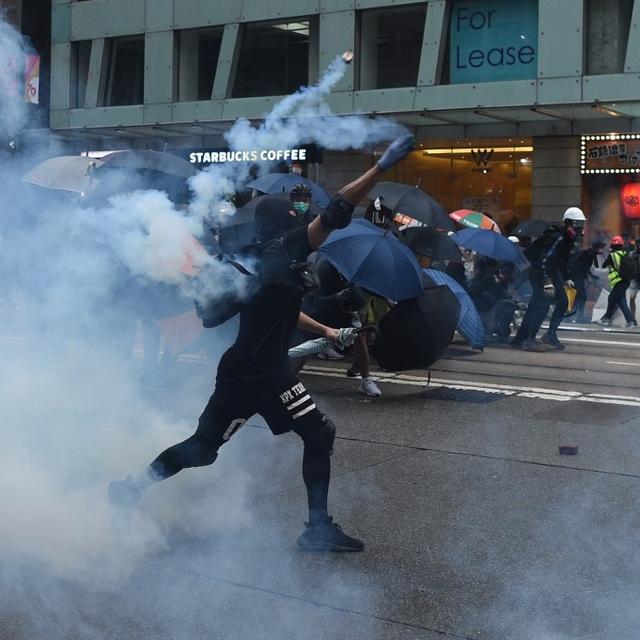 Un manifestant renvoie du gaz lacrymogène en direction de la police à Hong Kong. [AFP - Mohd Rasfan]