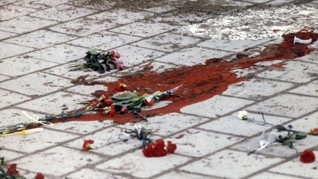 Photo prise le 1er mars 1986 montrant une mare de sang et des fleurs à l'endroit de Sveavagen (Stockholm, Suède), où l'assassinat du premier ministre Olof Palme eut lieu alors qu'il rentrait chez lui avec sa femme. [Keystone / EPA - LEIF SCHROEDER]