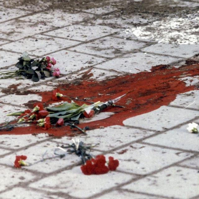 Photo prise le 1er mars 1986 montrant une mare de sang et des fleurs à l'endroit de Sveavagen (Stockholm, Suède), où l'assassinat du premier ministre Olof Palme eut lieu alors qu'il rentrait chez lui avec sa femme. [Keystone / EPA - LEIF SCHROEDER]