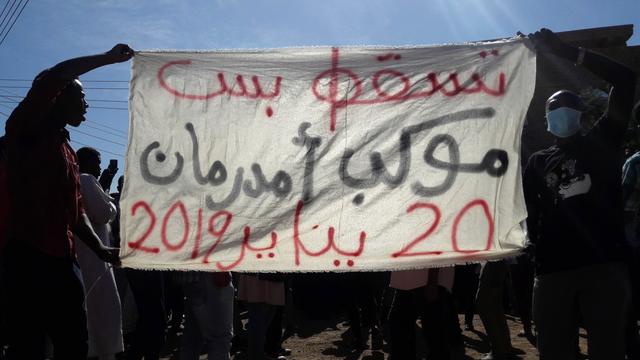 Des personnes brandissent une banière demandant un changement de régime lors d'une manifestation anti-gouvernementale à Omdurman au Soudan. [Stringer/AFP]