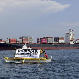 "Les Philippines ne sont pas un dépotoir!", c'est ce que dit ce panneau, devant un cargo qui renvoie plusieurs tonnes de déchets expédiés par le Canada. [Keystone /AP]