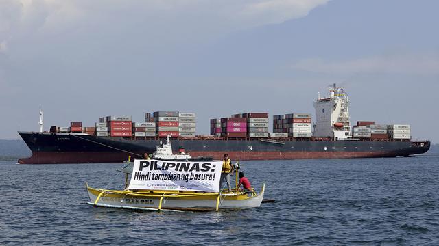 "Les Philippines ne sont pas un dépotoir!", c'est ce que dit ce panneau, devant un cargo qui renvoie plusieurs tonnes de déchets expédiés par le Canada. [Keystone /AP]