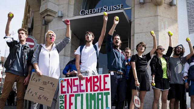 Des étudiants manifestent balle de tennis à la main, en référence au partenariat de Credit Suisse avec Roger Federer, contre les investissements de la banque dans des méthodes d'extraction du pétrole non-conventionnelles. [Keystone - Jean-Christophe Bott]