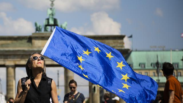 Une femme portant un drapeau européen devant la porte de Brandebourg à Berlin. [Keystone - AP Photo/Markus Schreiber]