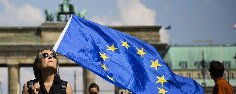 Une femme portant un drapeau européen devant la porte de Brandebourg à Berlin. [Keystone - AP Photo/Markus Schreiber]