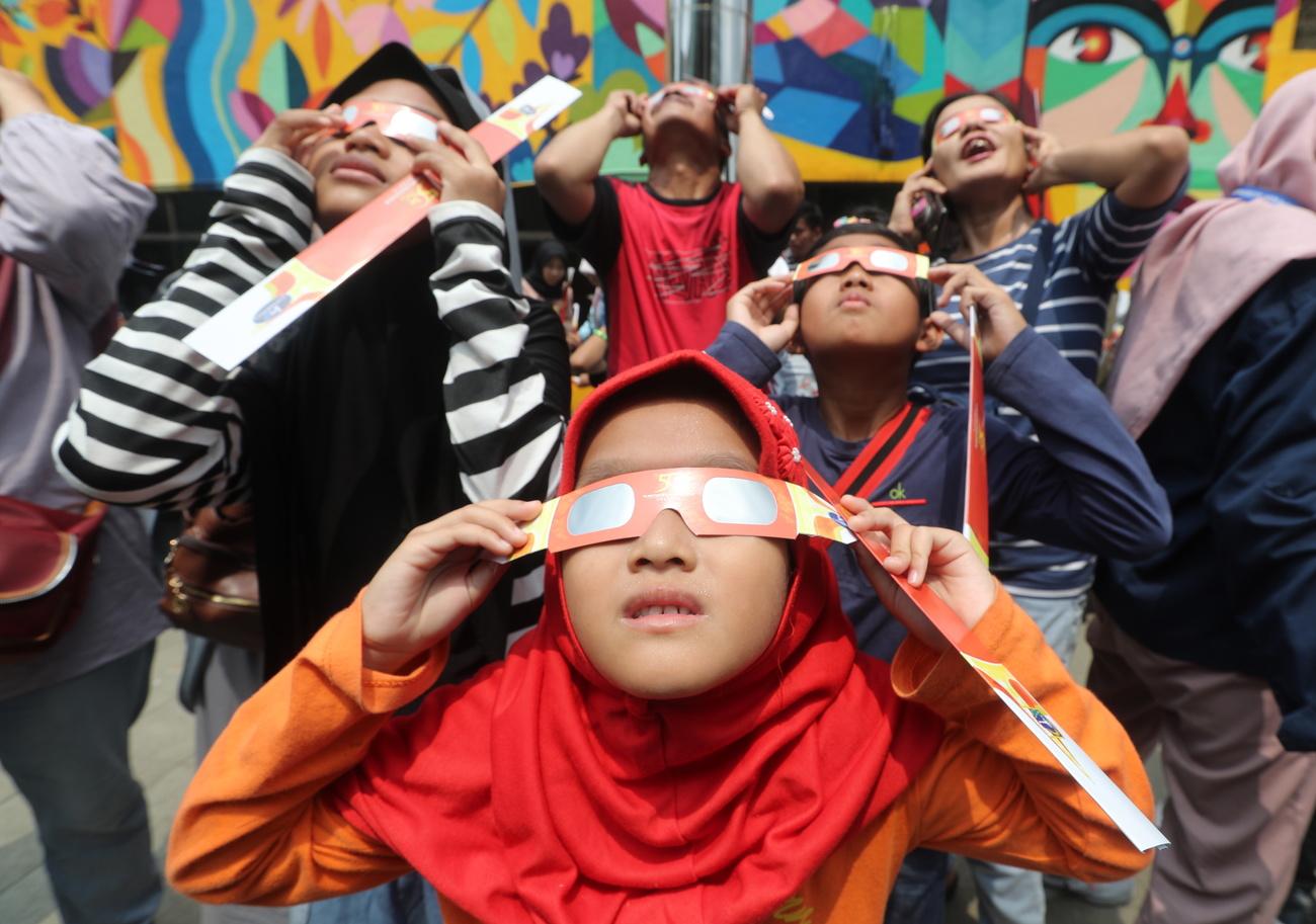 Des enfants observent l'éclipse annulaire depuis Jakarta, en Indonésie. [Keystone/epa - Bagus Indahono]
