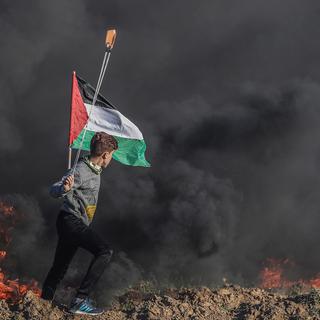 Vendredi 8 mars: un jeune Palestinien lance des pierres avec une fronde durant des affrontements avec l'armée israélienne près de la frontière entre la bande de Gaza et Israël. [Keystone - EPA/MOHAMMED SABER]