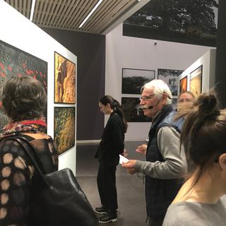 Yann Arthus-Bertrand distribue des guides dans les salles de son exposition à la fondation Opale à Lens. [RTS - Karine Vasarino]