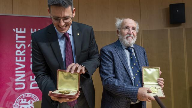 Les Prix Nobel de physique Didier Queloz (gauche) et Michel Mayor présentent leurs médailles à la presse à leur retour de Suède, le 14 décembre 2019 à l'aéroport de Genève. [Keystone - Martial Trezzini]