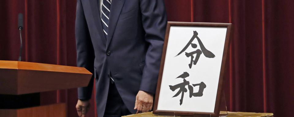 Le Premier ministre japonais, Shinzo Abe, regarde la calligraphie du nom de la nouvelle ère impériale, "Reiwa". [Keystone/ap photo - Eugene Hoshiko]