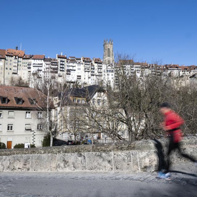 Une personne fait de la course à pieds en Basse-Ville de Fribourg. [Keystone - Adrien Perritaz]