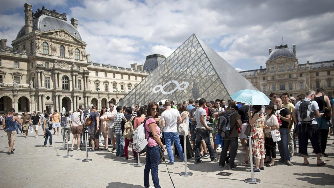 Des visiteurs en train de faire la queue pour visiter le Louvre à Paris en 2013. [Keystone - EPA/IAN LANGSDON]